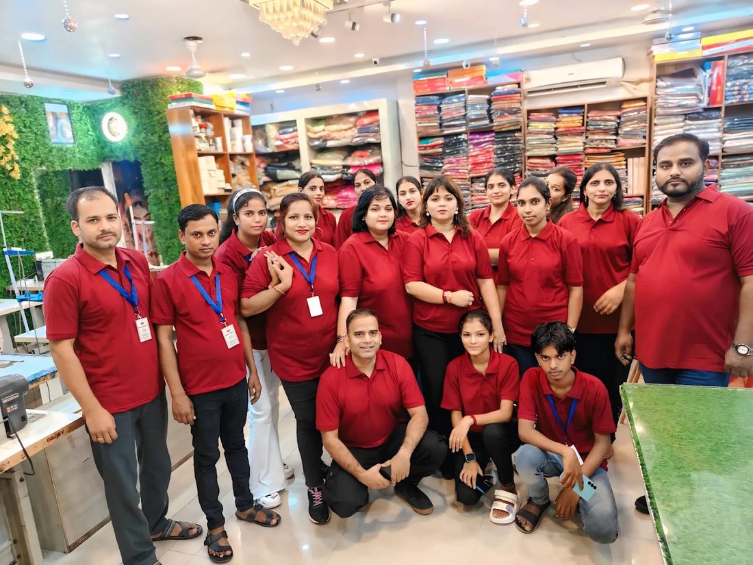 The Adaa Bazaar team, some twenty of them in the shop's red uniform, standing together among the shelves of fabric.